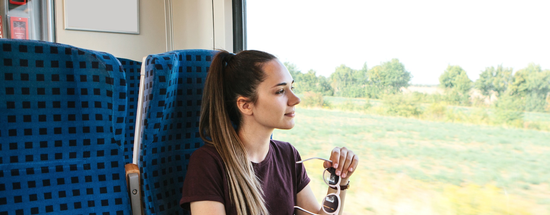 Junge Frau fährt mit dem Zug und schaut aus dem Fenster